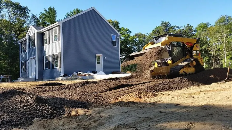 Skid steer grading beside a new home
